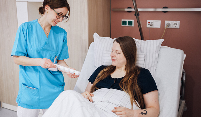 Pflegerin des Caritas-Krankenhaus St. Lukas im Gespräch mit Patientin im Krankenbett