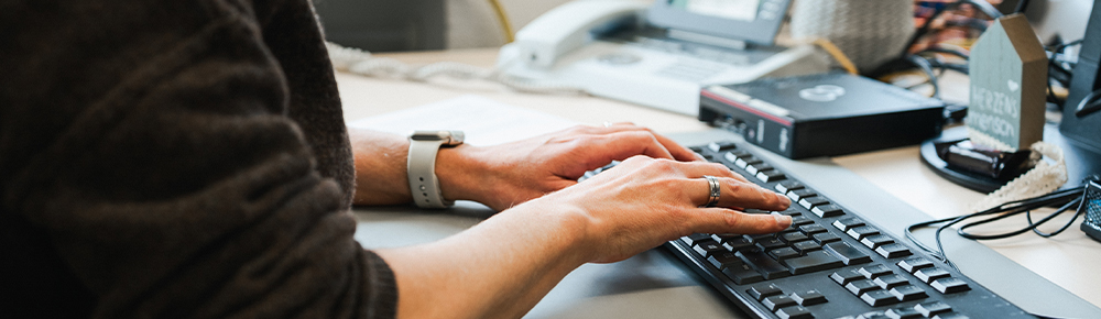 Mitarbeitende der Verwaltung tippt auf einer Tastatur am Computer